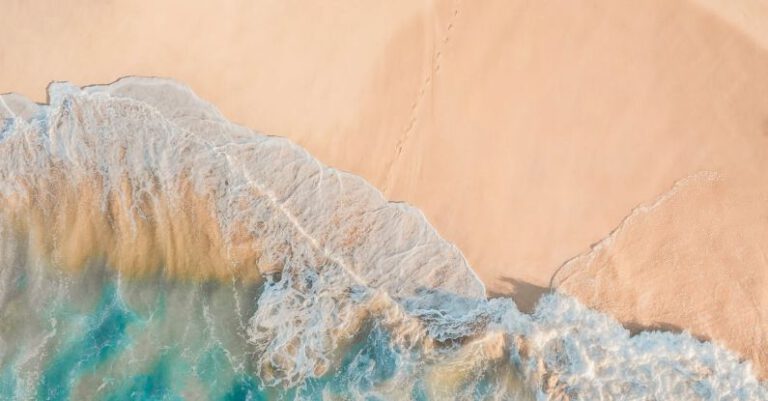 Shorelines - Drone view of anonymous person walking along sandy beach of turquoise sea in sunny day