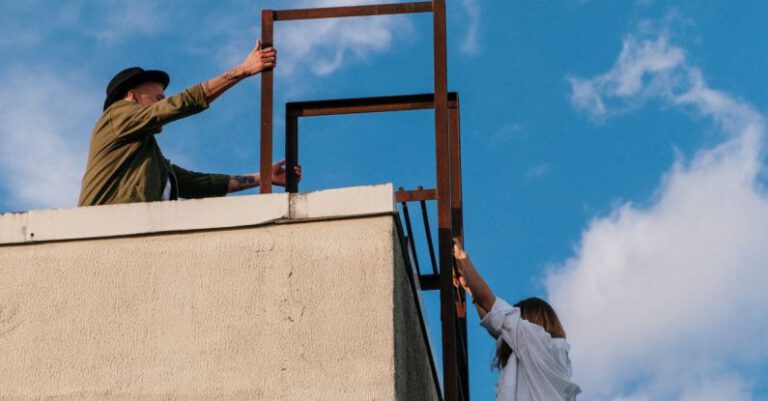 Explorers - Man in Brown Jacket and Blue Denim Jeans Climbing on Brown Concrete Wall