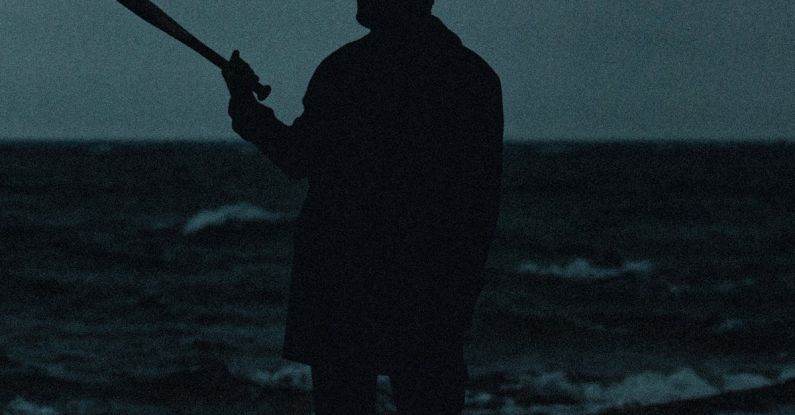 Mysterious Places - A man holding a baseball bat in front of the ocean