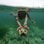 Diving Expedition - A woman is underwater with her hands in the water