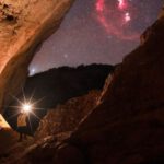 Discoveries - Person Walking with Flashlight among Rocks at Night