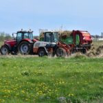 Acidification - a red tractor pulling a trailer of hay through a field