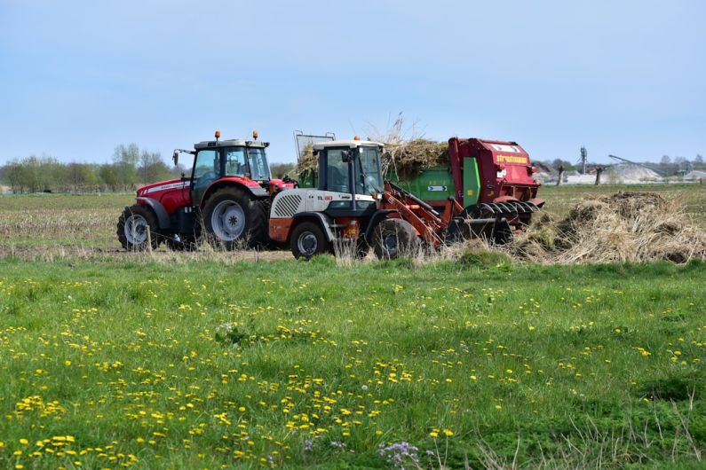 Acidification - a red tractor pulling a trailer of hay through a field